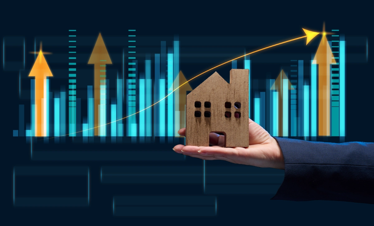 Hand holding house model with growth chart